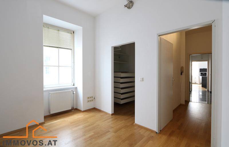 Helles Zimmer mit Parkettboden und Zugang zu einem begehbaren Kleiderschrank, ideal als Schlafzimmer.