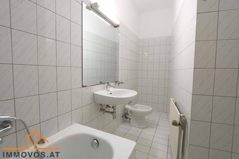 Helles Badezimmer mit Badewanne, Bidet, Waschbecken und Spiegel, komplett gefliest.