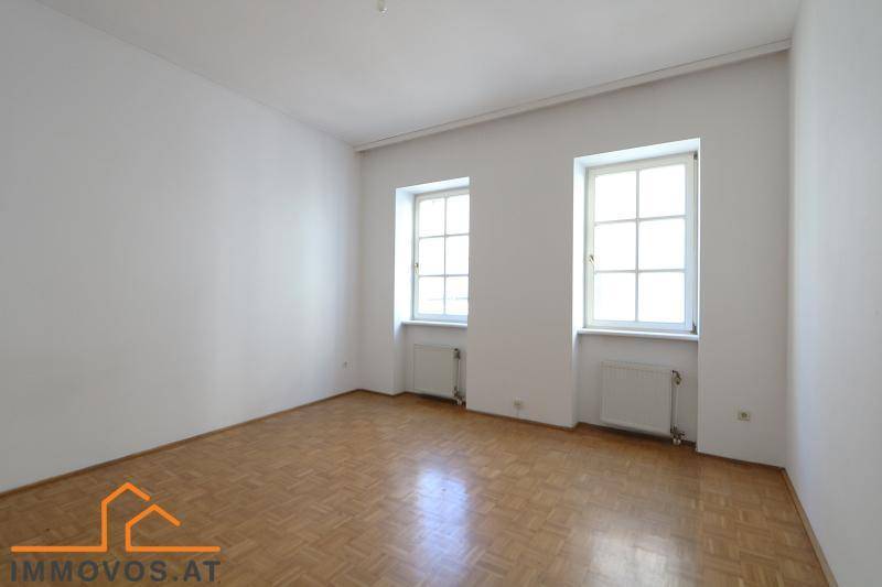 Ruhiges Schlafzimmer mit klassischem Parkettboden und zwei Fenstern, bietet viel natürliches Licht.