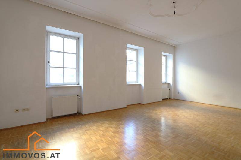 Geräumiges, helles Zimmer mit klassischem Parkettboden und hohen Fenstern, bereit zur individuellen Gestaltung.