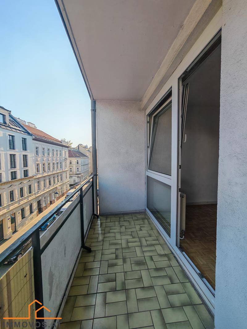 Langer Balkon mit Fliesen und Blick auf die gegenüberliegenden Wohngebäude.
