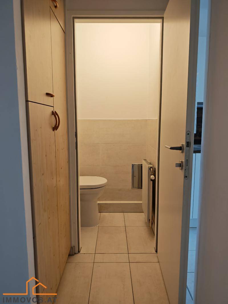 Separates WC mit hellen Fliesen und integriertem Spülkasten.