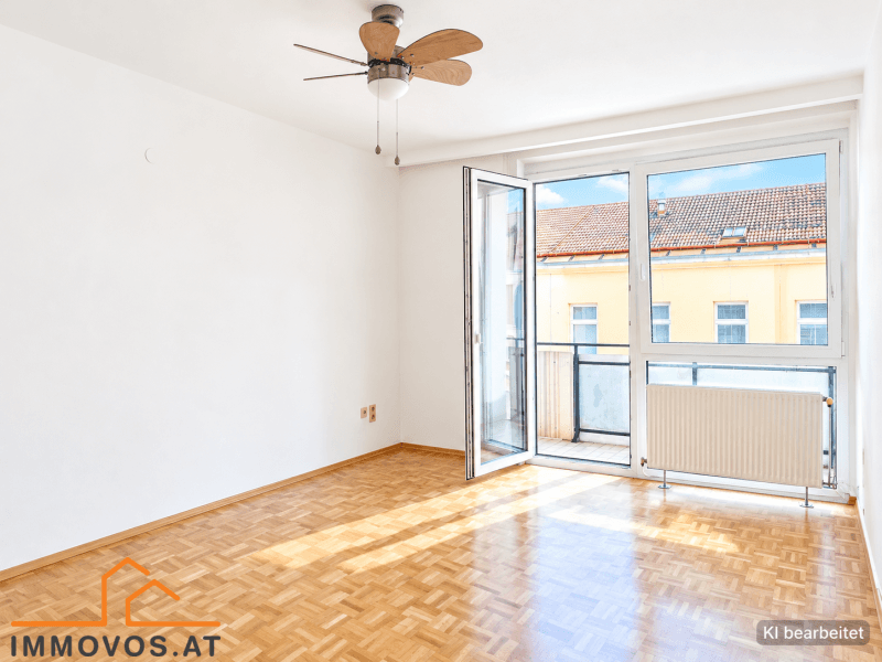Helles Wohnzimmer mit Parkettboden, Deckenventilator und Zugang zum Balkon.