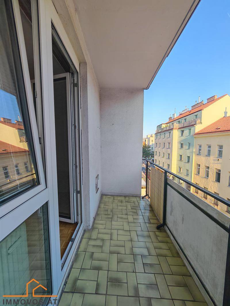 Schmaler Balkon mit Fliesenboden und Blick auf die umliegenden Gebäude.