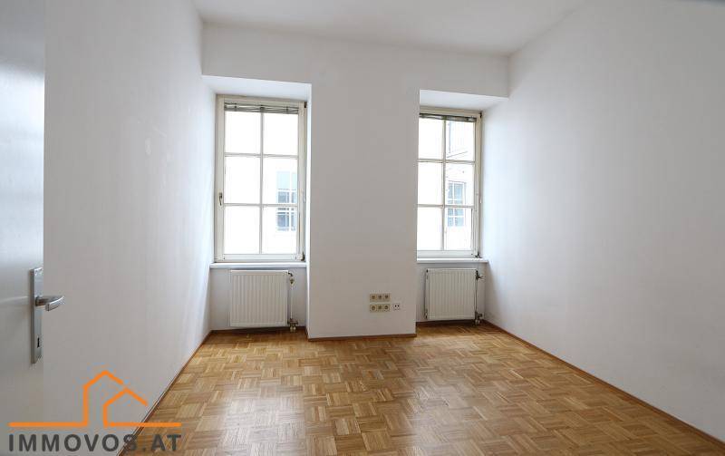 Geräumiges Zimmer mit Parkettboden und zwei großen Fenstern, bietet viel natürliches Licht.