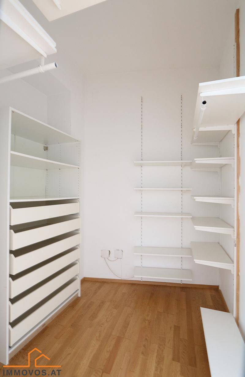 Geräumiger begehbarer Kleiderschrank mit weißen Regalen und Schubladen für optimale Organisation.