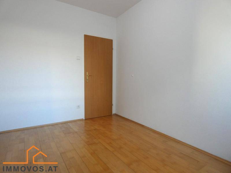 Leeres Zimmer mit Holzboden und einer Holztür, bereit für individuelle Gestaltung.