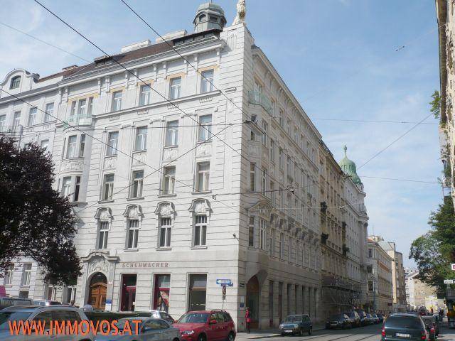 Historisches Eckgebäude mit reich verzierter Fassade und vielen Fenstern an einer belebten Straße.
