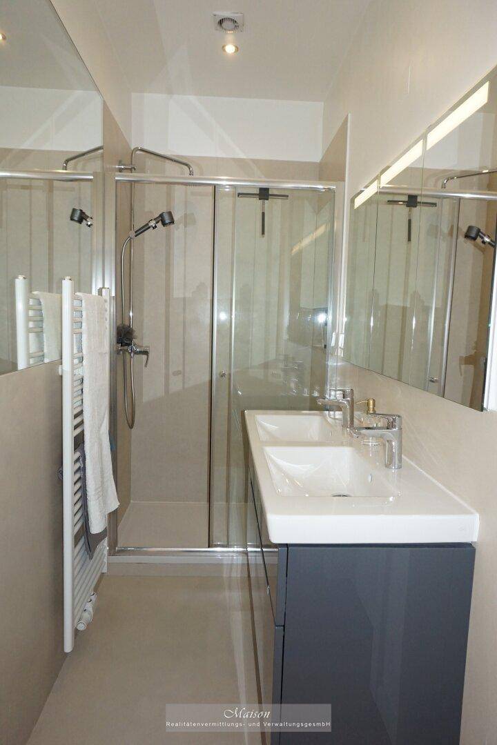 Modernes Badezimmer mit Duschkabine, Einzelwaschbecken und beheiztem Handtuchhalter.