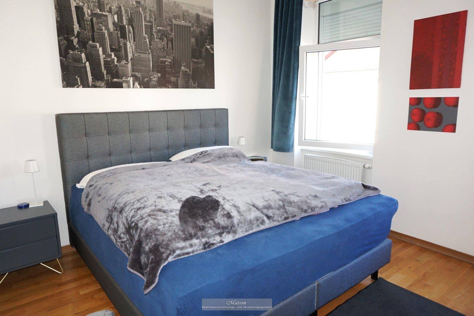 Gemütliches Schlafzimmer mit großem Doppelbett, Holzboden und einem Fenster mit Blick nach draußen.