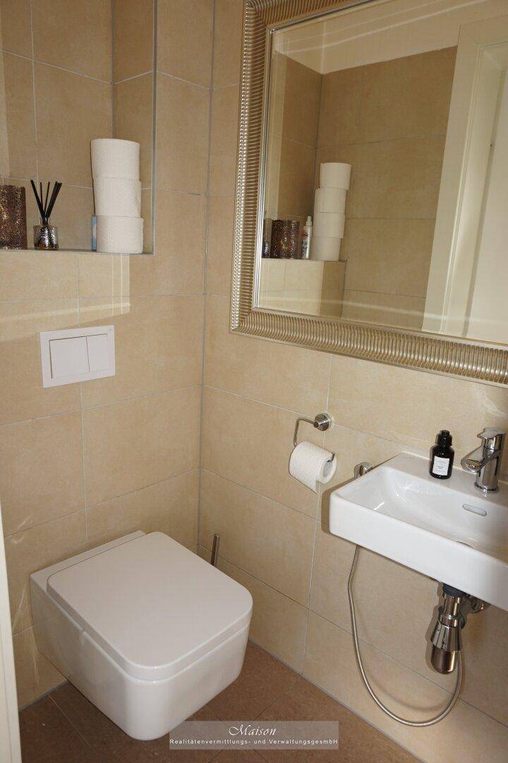 Kleines Gäste-WC mit modernem Wand-WC, Waschbecken und großem Spiegel.