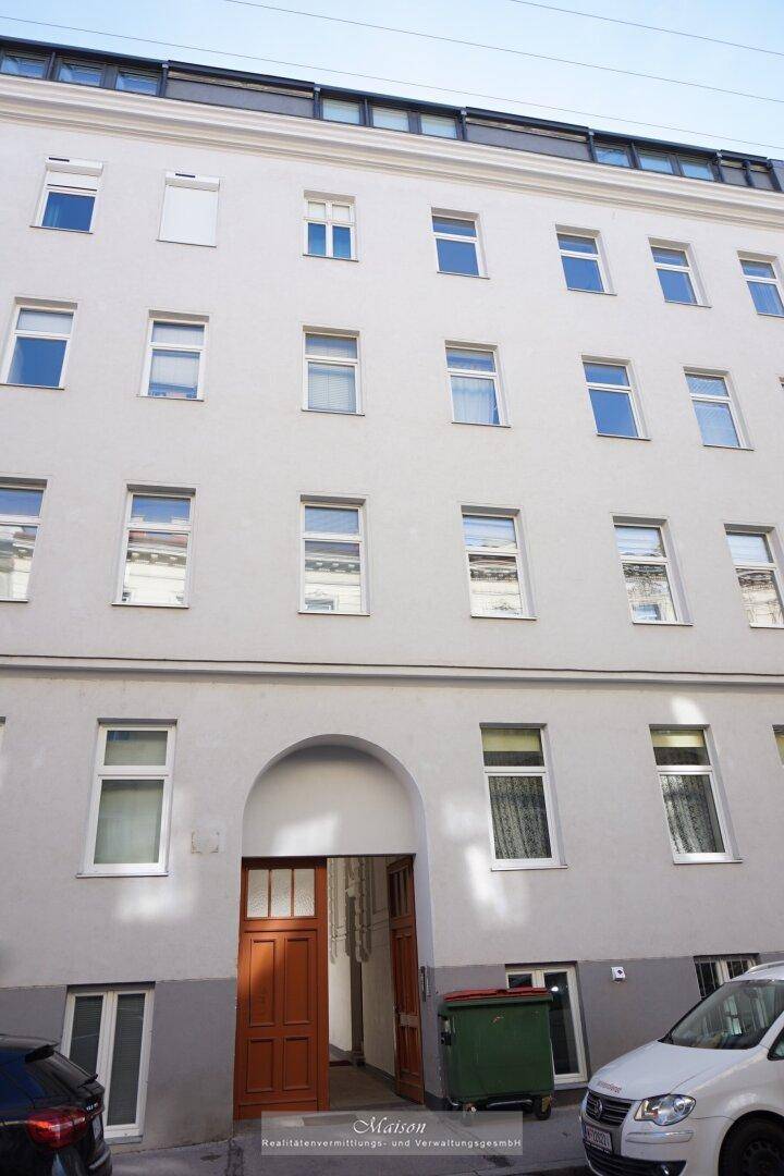 Fassade eines Mehrfamilienhauses mit vielen Fenstern und einem markanten Eingangsbereich.