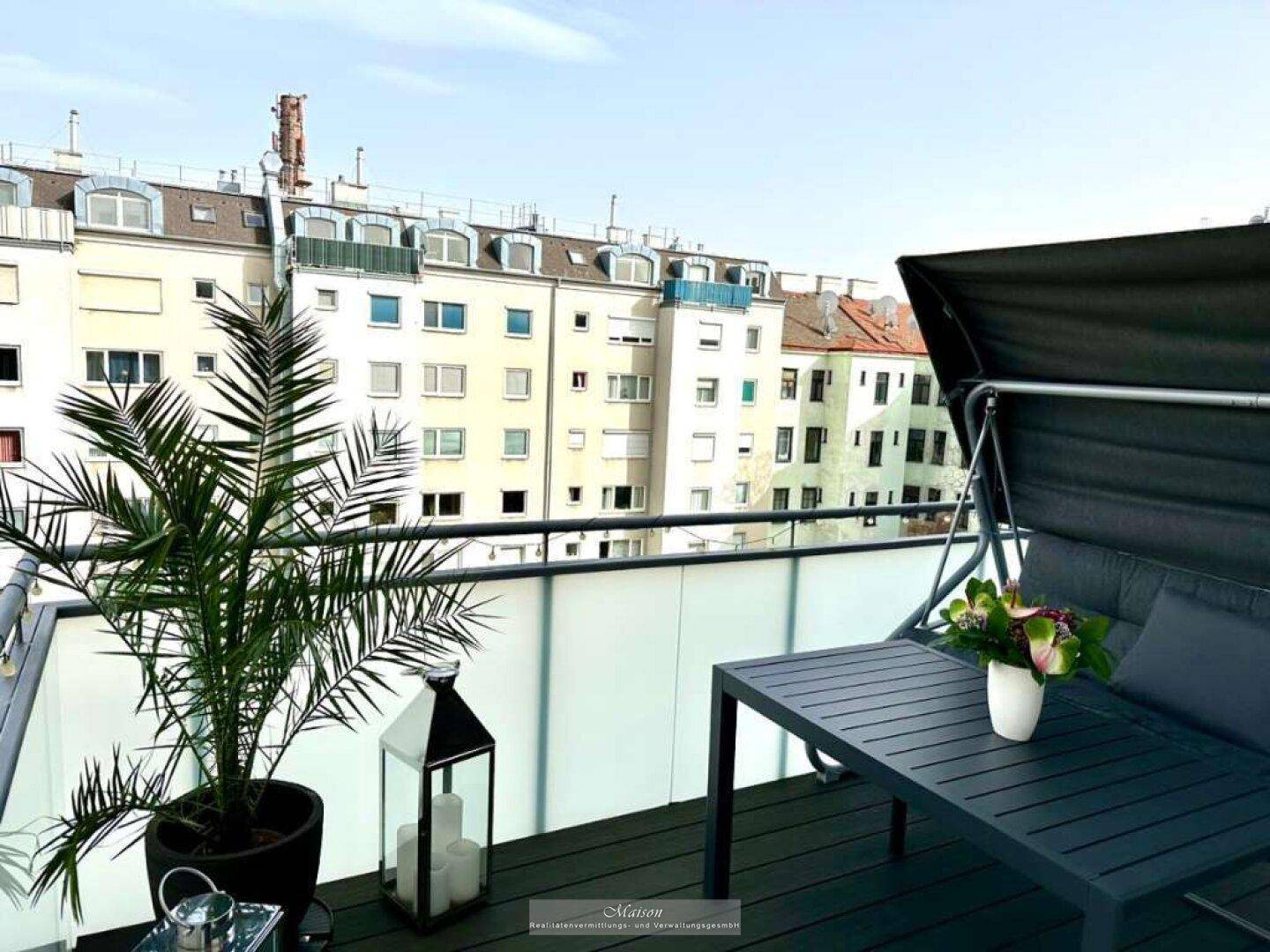 Möblierter Balkon mit Stadtblick und einer Palme, ideal zum Entspannen im Freien.