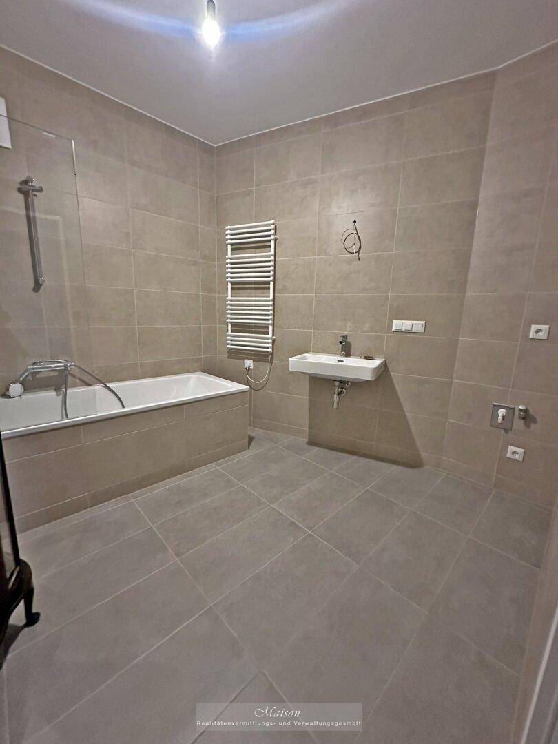 Modernes Badezimmer mit Badewanne, Waschbecken und beheiztem Handtuchhalter.