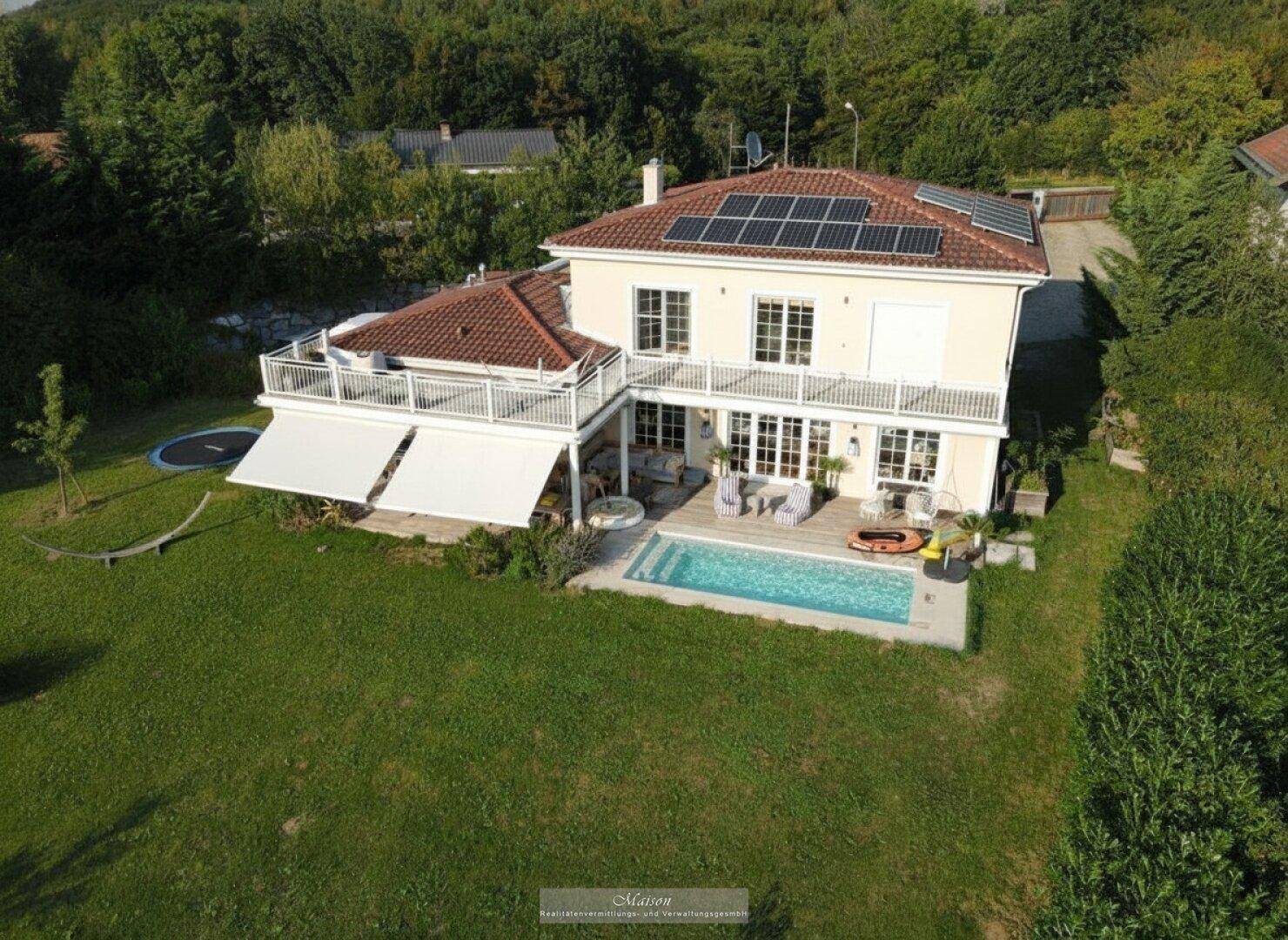 Ansicht des Hauses von oben mit Pool, großer Terrasse und grüner Umgebung.