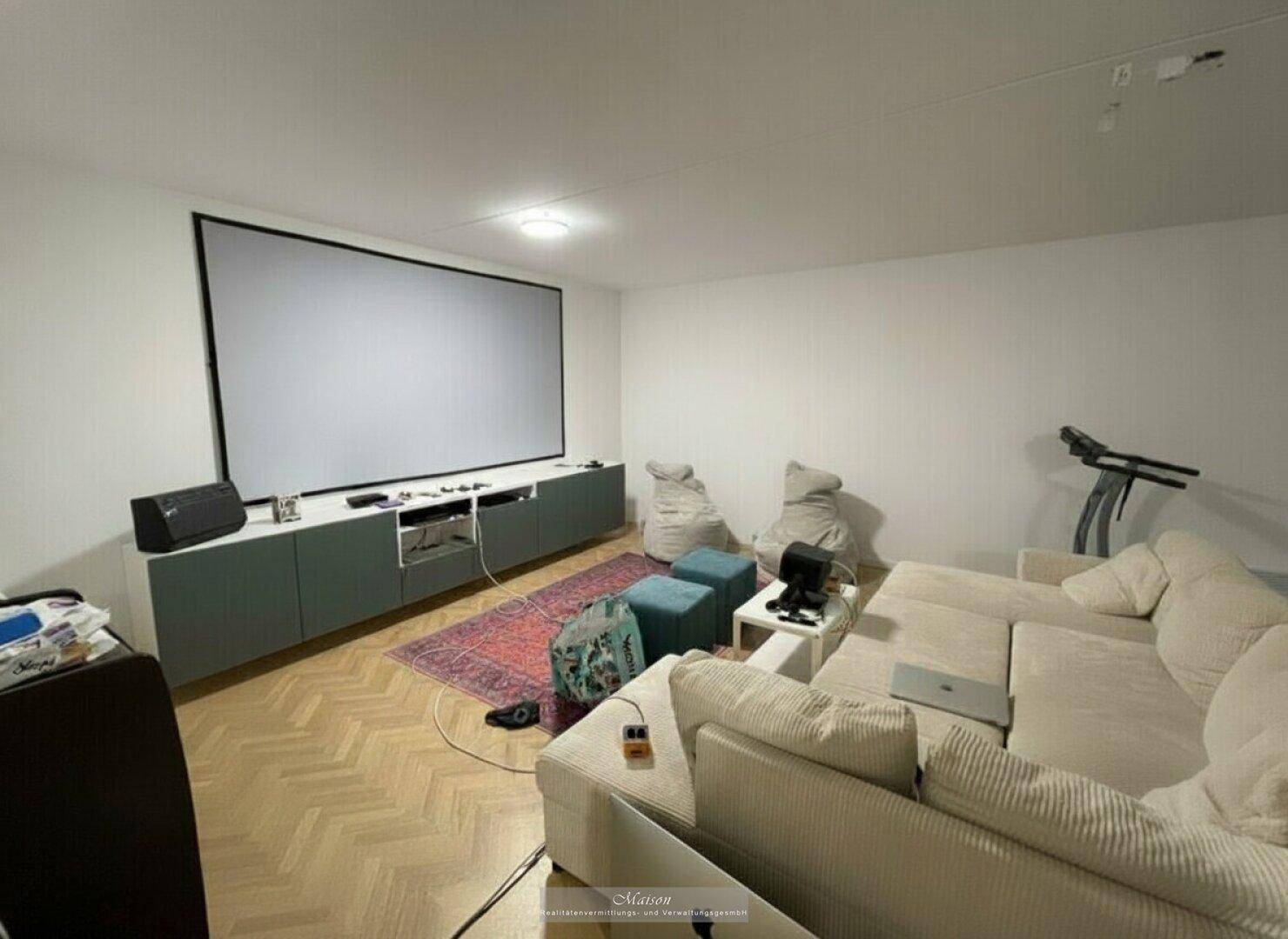 Gemütlicher Medienraum mit großer Leinwand, bequemen Sofas und hellem Holzboden.