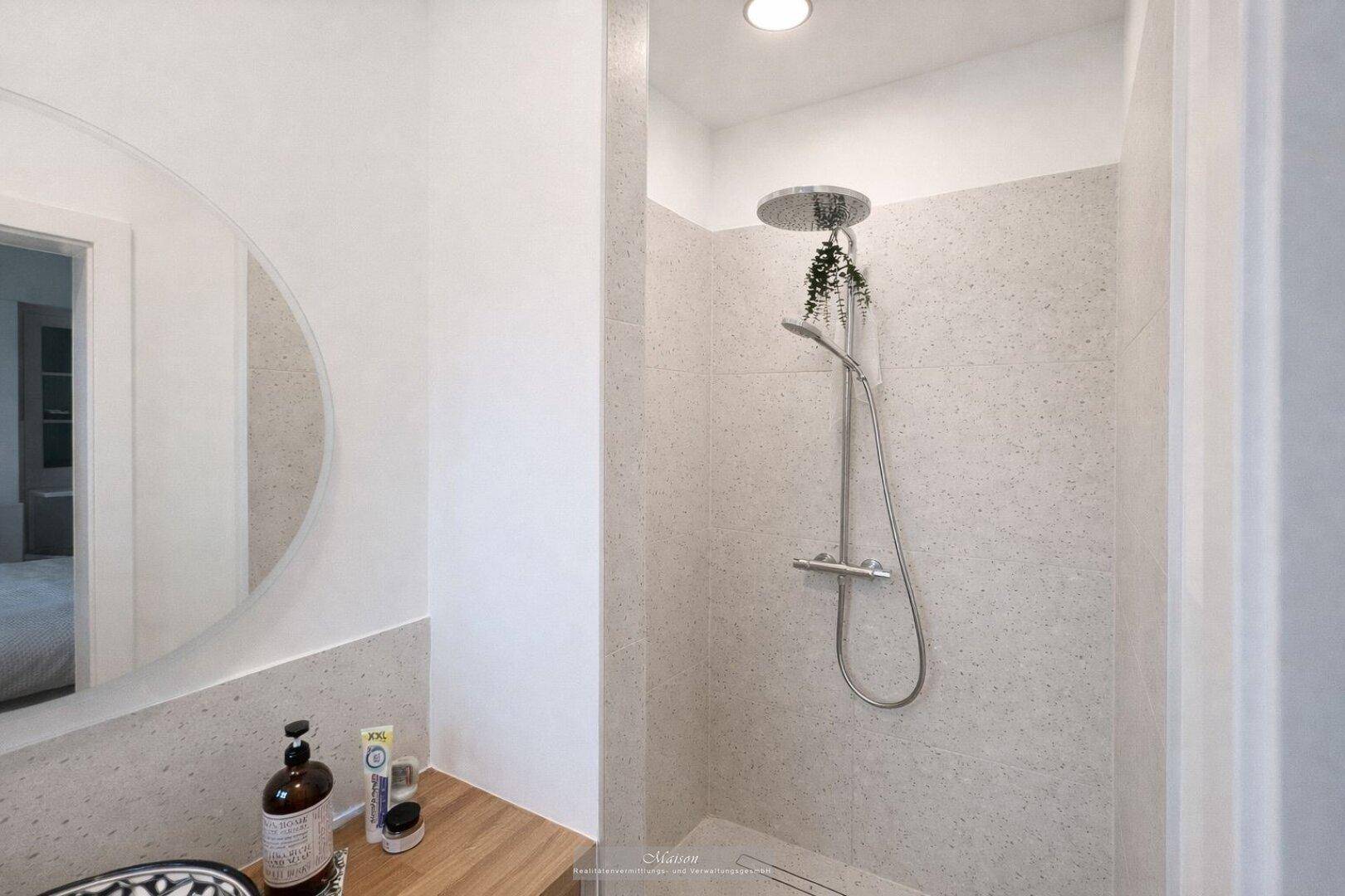 Modernes Badezimmer mit begehbarer Dusche und runden Spiegeln.