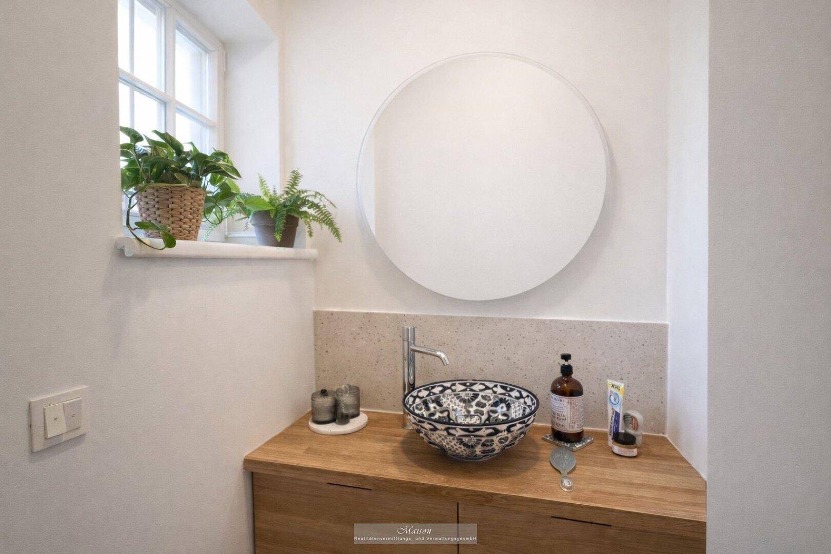 Badezimmer mit modernem Waschbecken, Holzunterschrank und Fenster.
