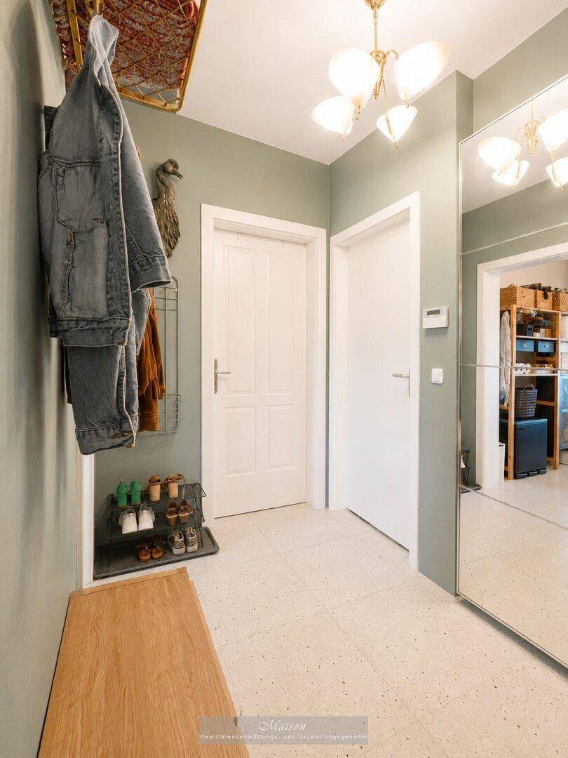 Eingangsbereich mit großem Spiegel, Schuhregal und heller Deckenleuchte.