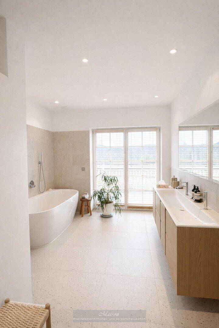 Geräumiges Badezimmer mit Doppelwaschbecken, Badewanne und großem Fenster.