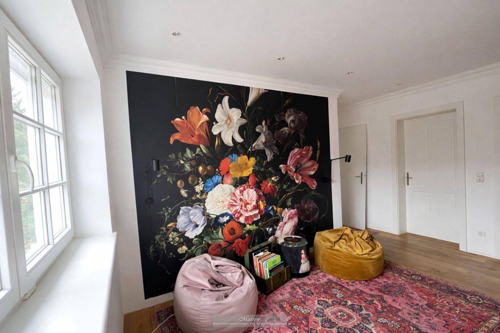 Heller Raum mit großer Blumenwandtapete, Sitzsäcken und Teppich.