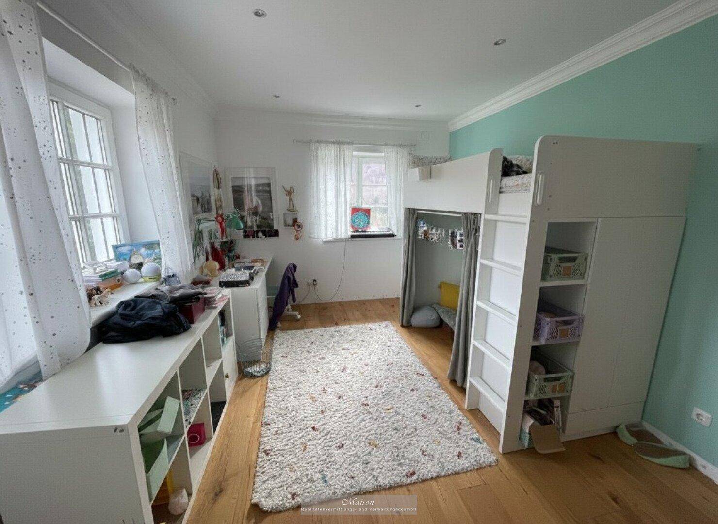 Kinderzimmer mit Hochbett, Schreibtisch und hellem Parkettboden.