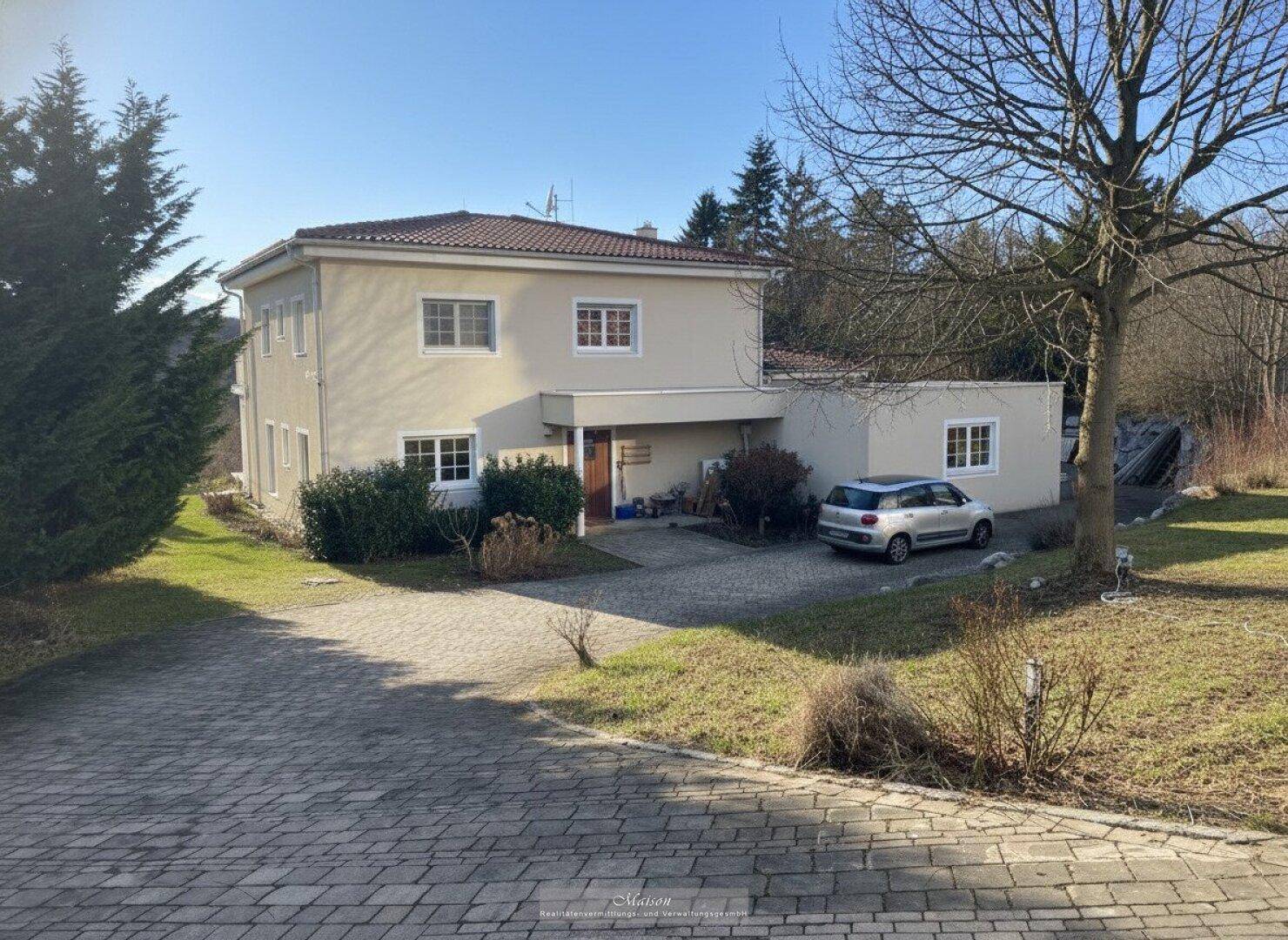Vorderansicht des Hauses mit gepflasterter Auffahrt und umgebenden Bäumen im Winter.