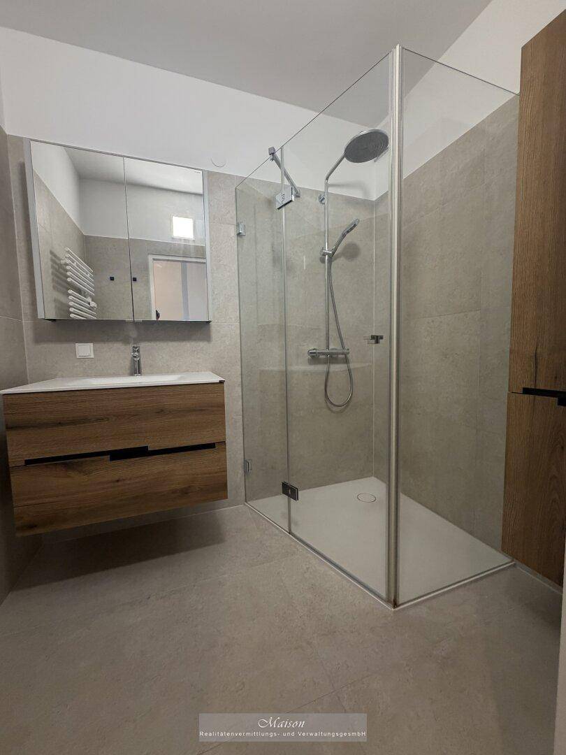 Modernes Badezimmer mit begehbarer Dusche, Holzwaschtisch und beheiztem Handtuchhalter.