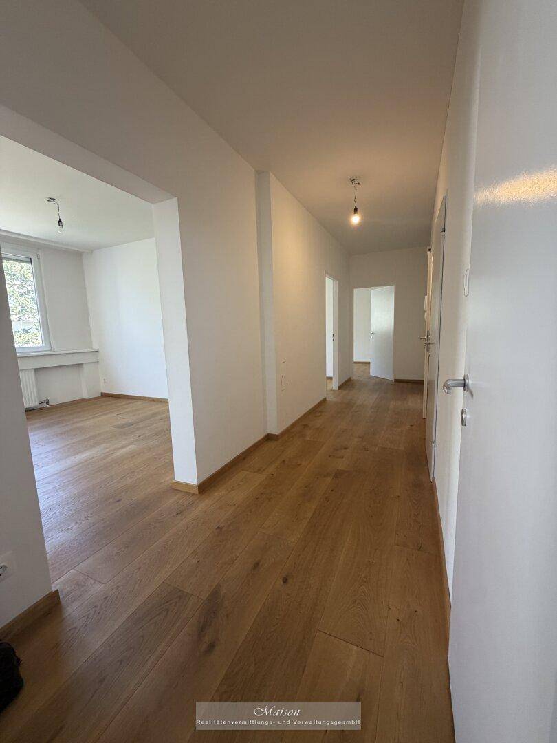 Langer, heller Flur mit neuem Holzparkettboden, der zu verschiedenen Zimmern der Wohnung führt.