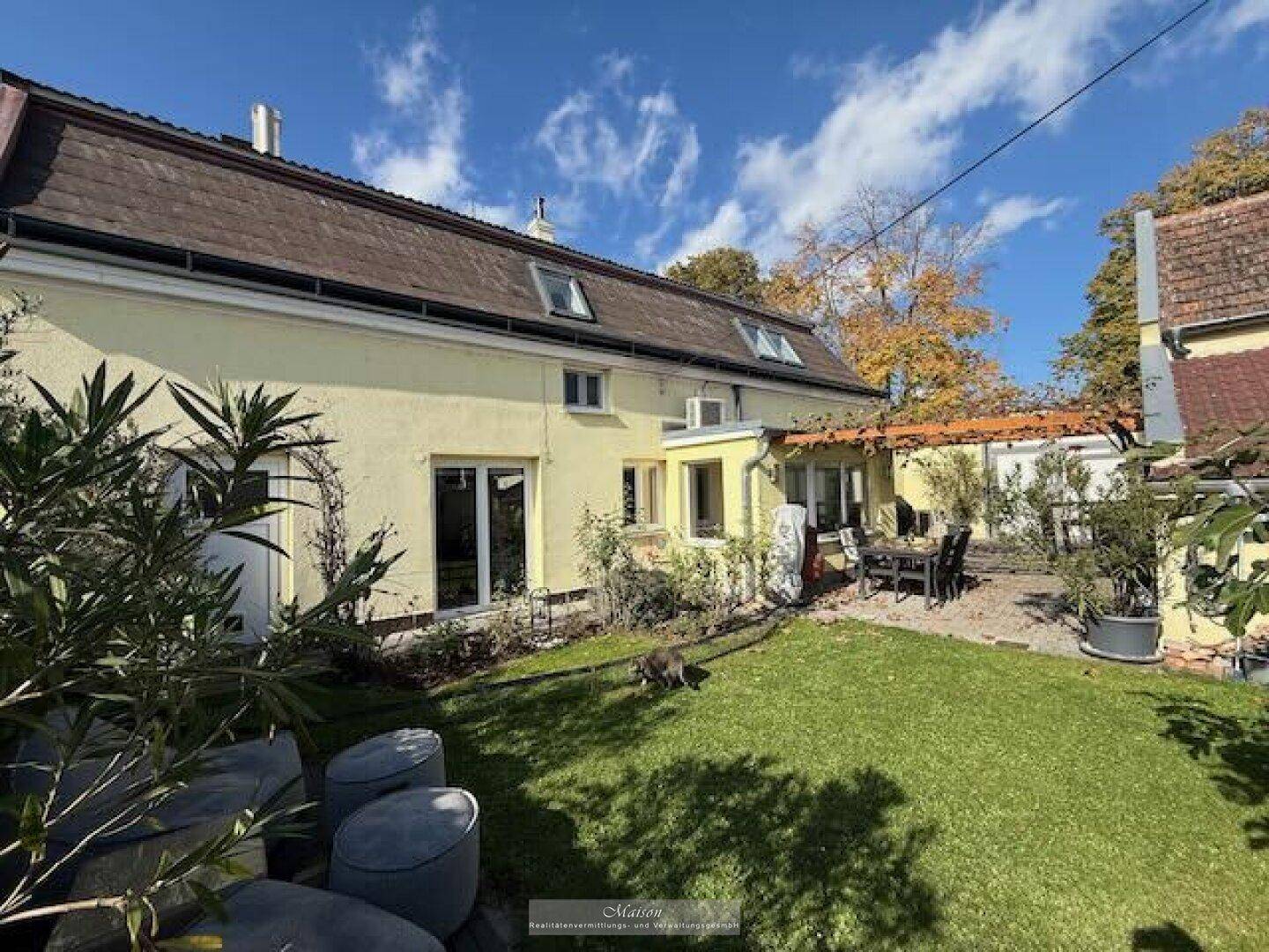 Ansicht des Hauses vom gepflegten Garten aus mit Rasenfläche und Terrasse.