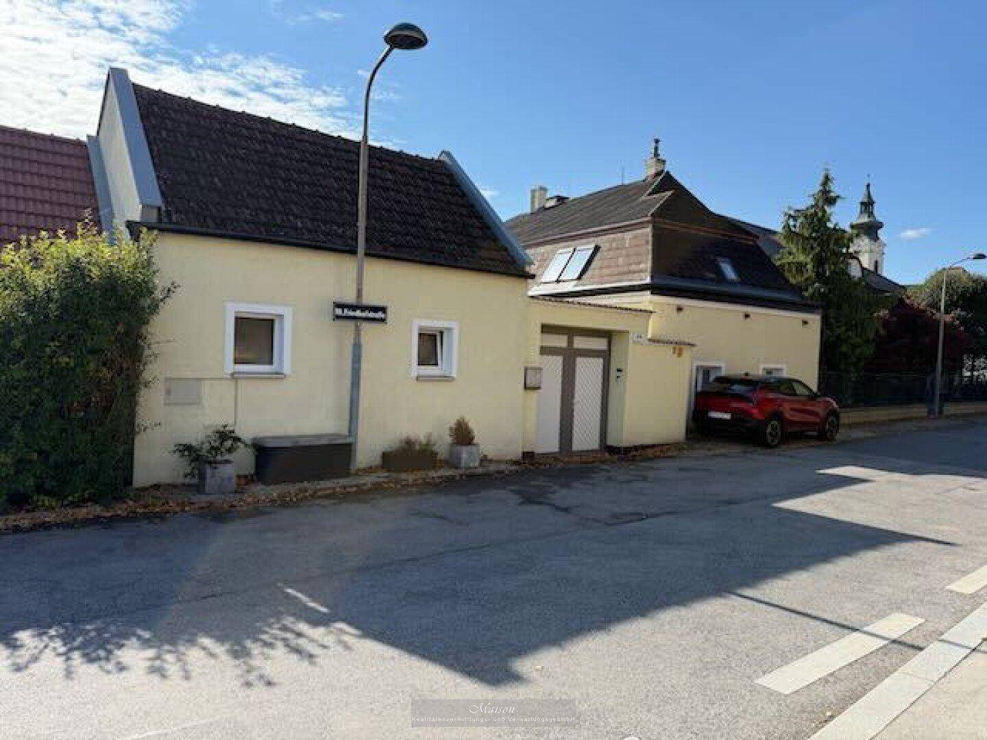 Ansicht des Hauses von der Straße aus mit traditioneller Architektur und Mansarddach.