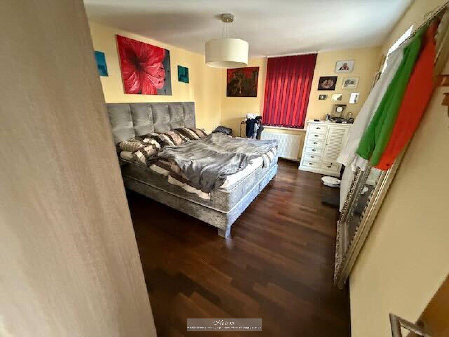 Gemütliches Schlafzimmer mit Doppelbett, Holzboden und farbenfroher Dekoration.