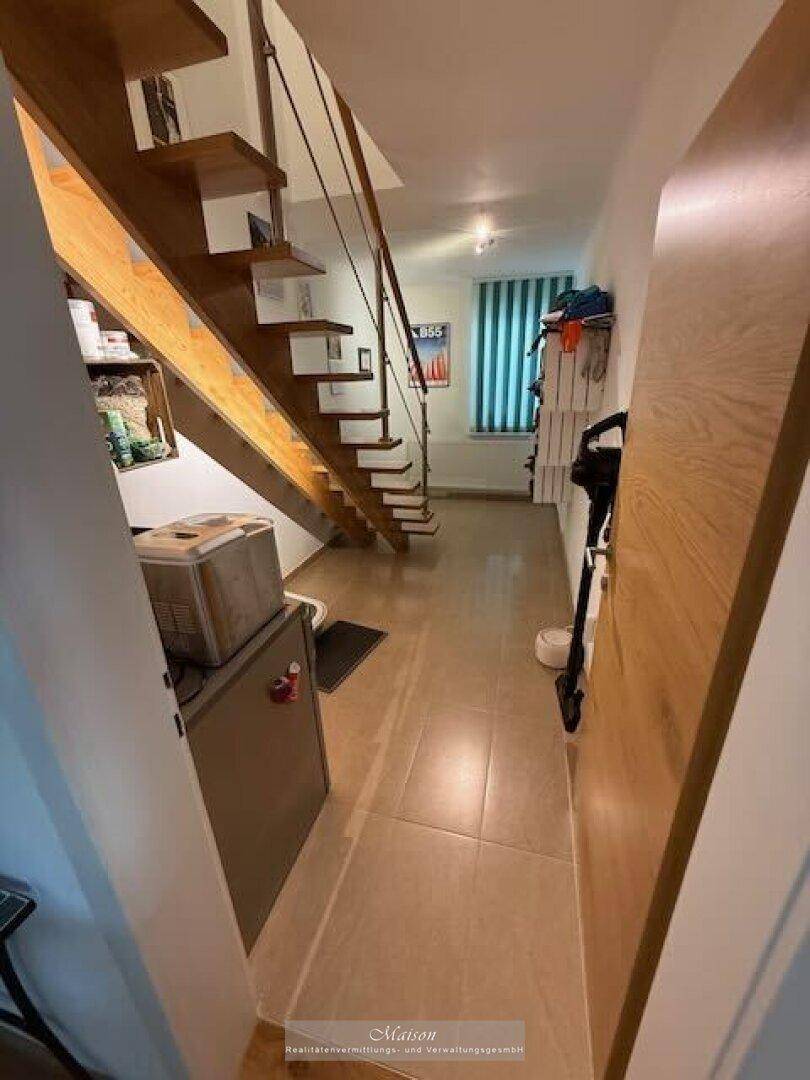 Heller Flur mit moderner Holztreppe und Fliesenboden.