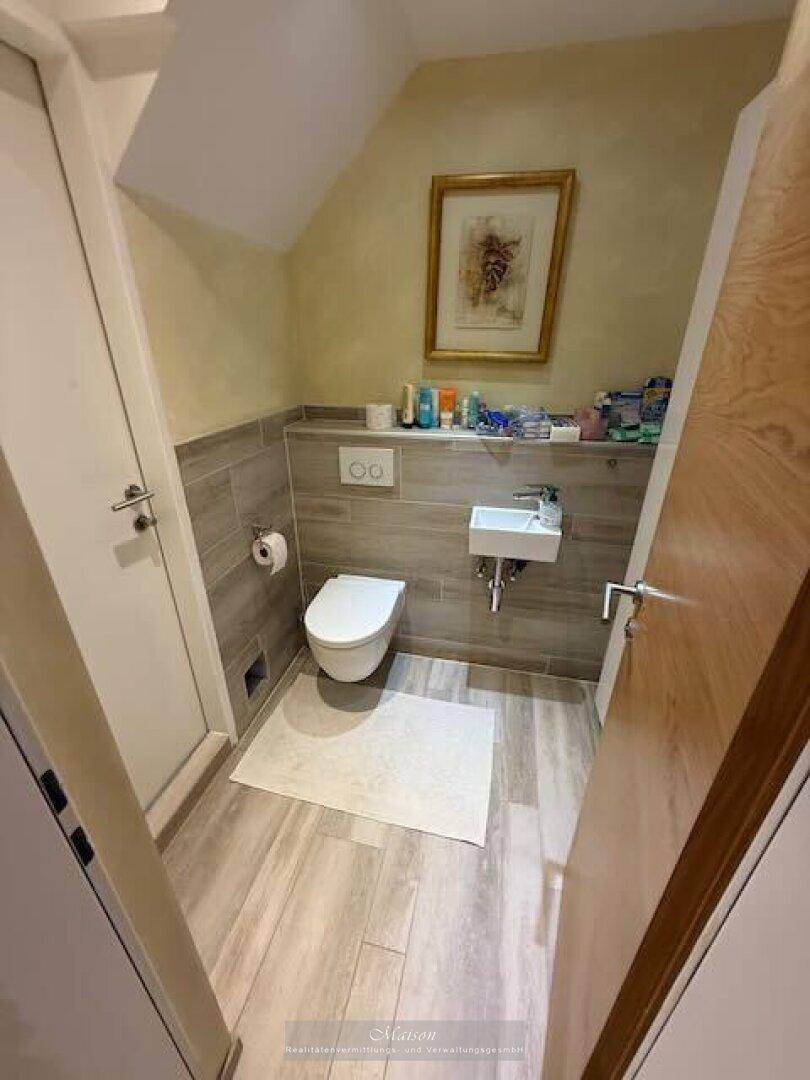 Kleines Gäste-WC mit Wand-WC, Waschbecken und modernen Fliesen.