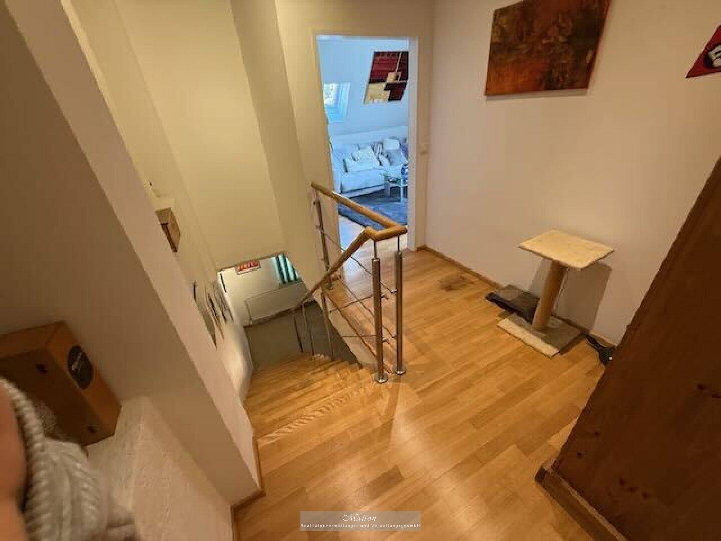Heller Flur mit Holztreppe, die in den Keller und zu den oberen Etagen führt.