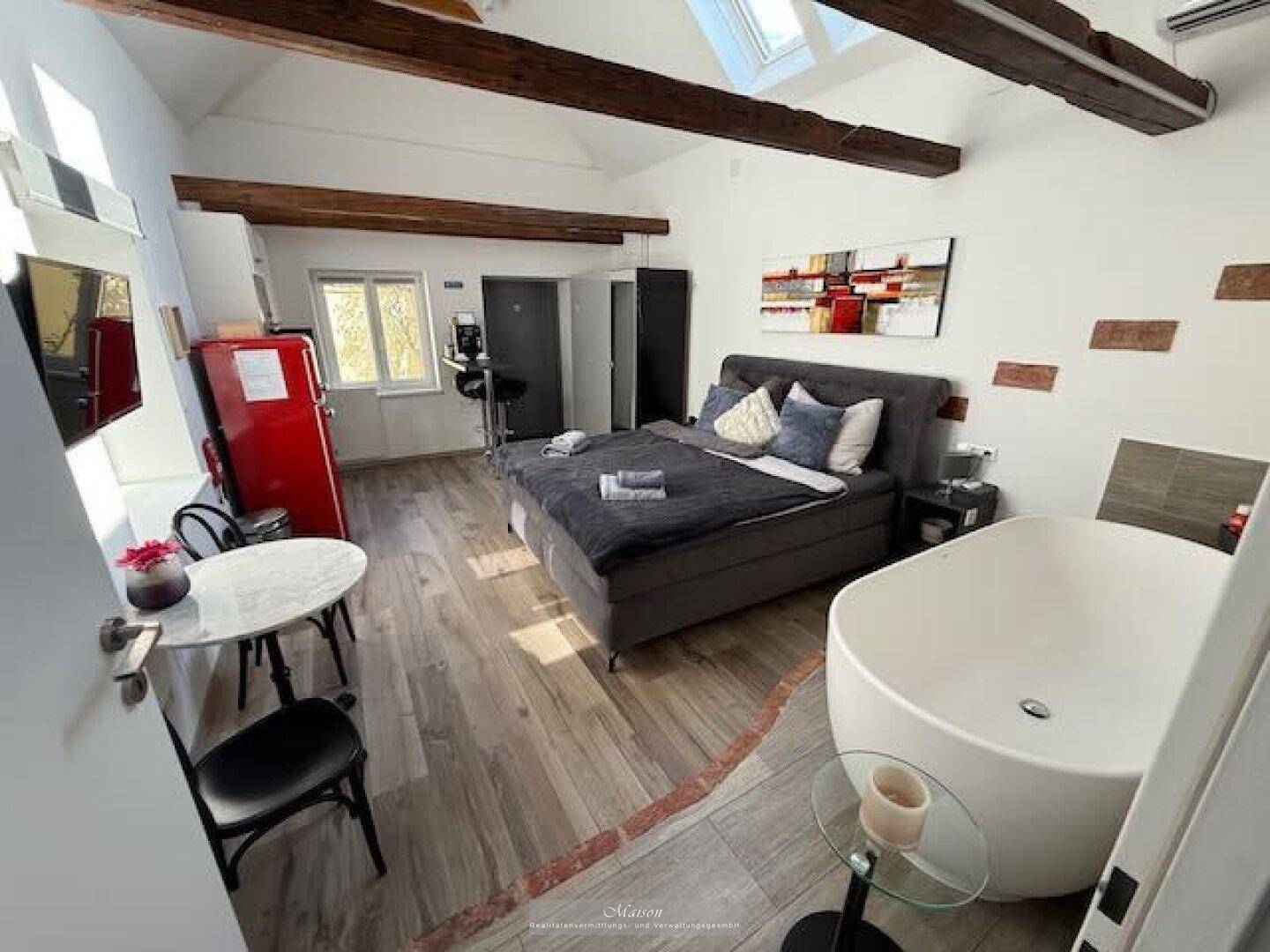Einzigartiges Schlafzimmer im Dachgeschoss mit freistehender Badewanne, Holzbalken und Dachfenstern.