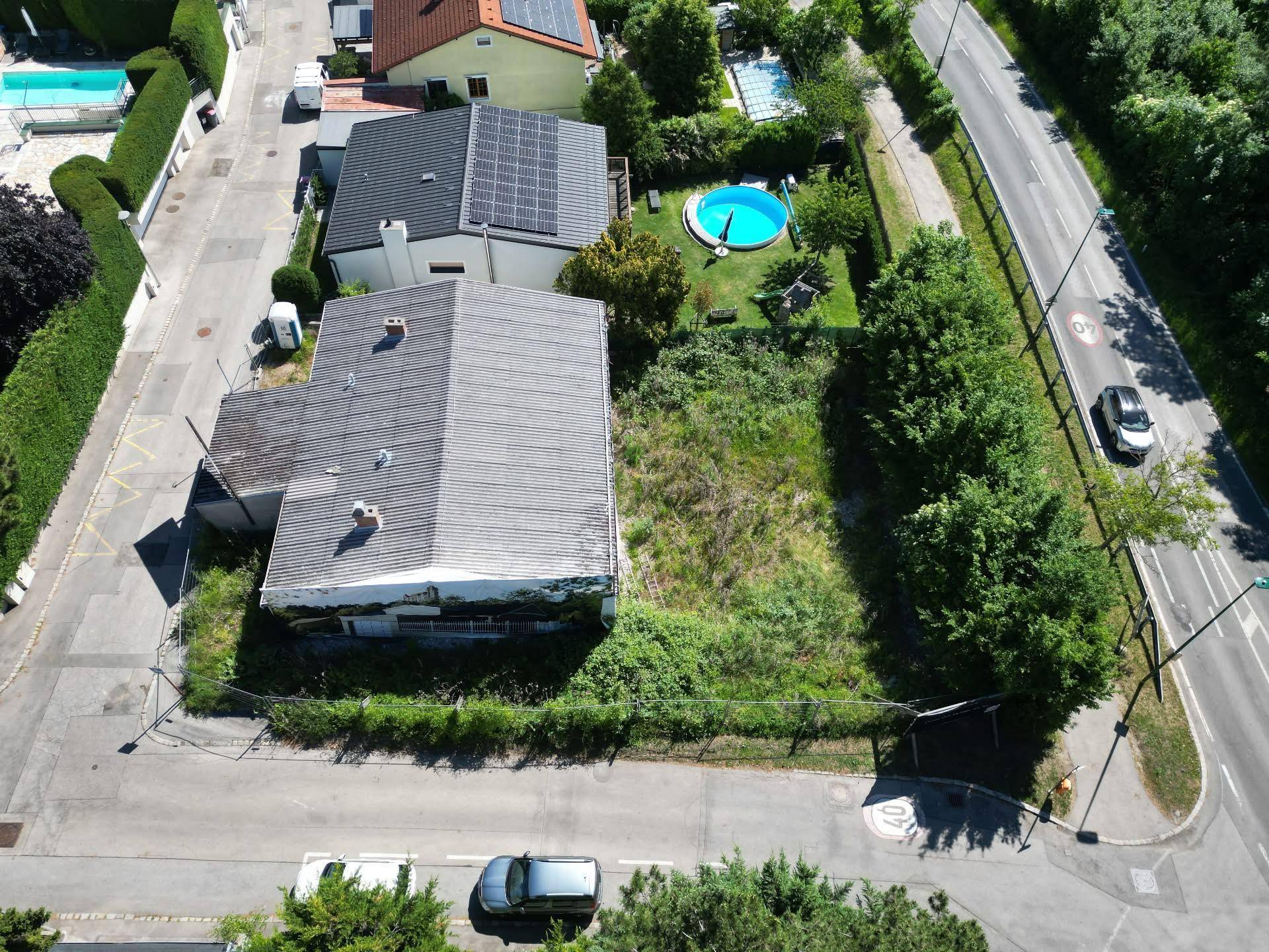 Weitläufige Luftaufnahme eines Grundstücks mit angrenzendem Nachbarhaus, Pool und Solaranlage.