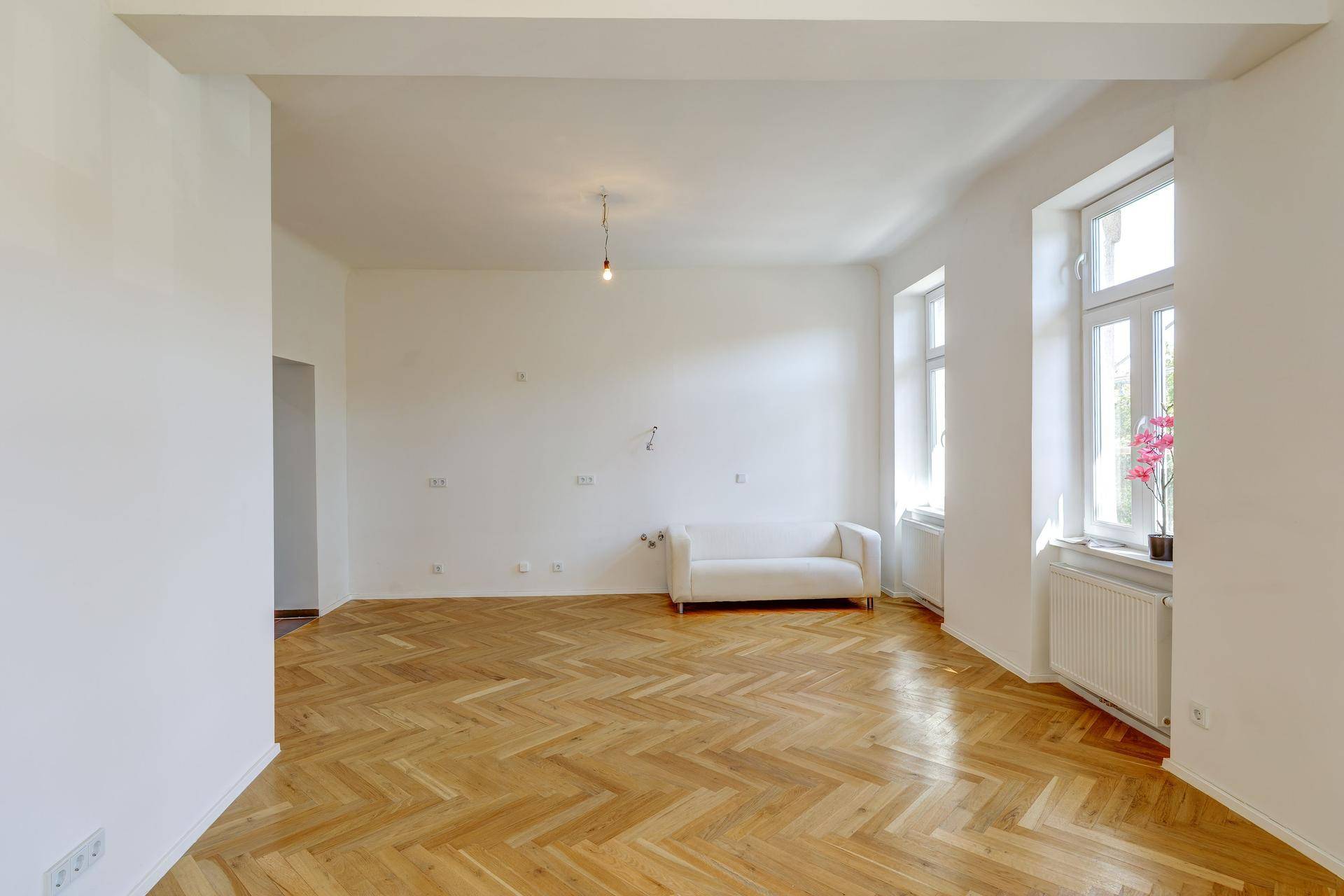 Heller Wohnraum mit Fischgrätparkett, hohen Decken und großen Fenstern, bereit zur individuellen Gestaltung.