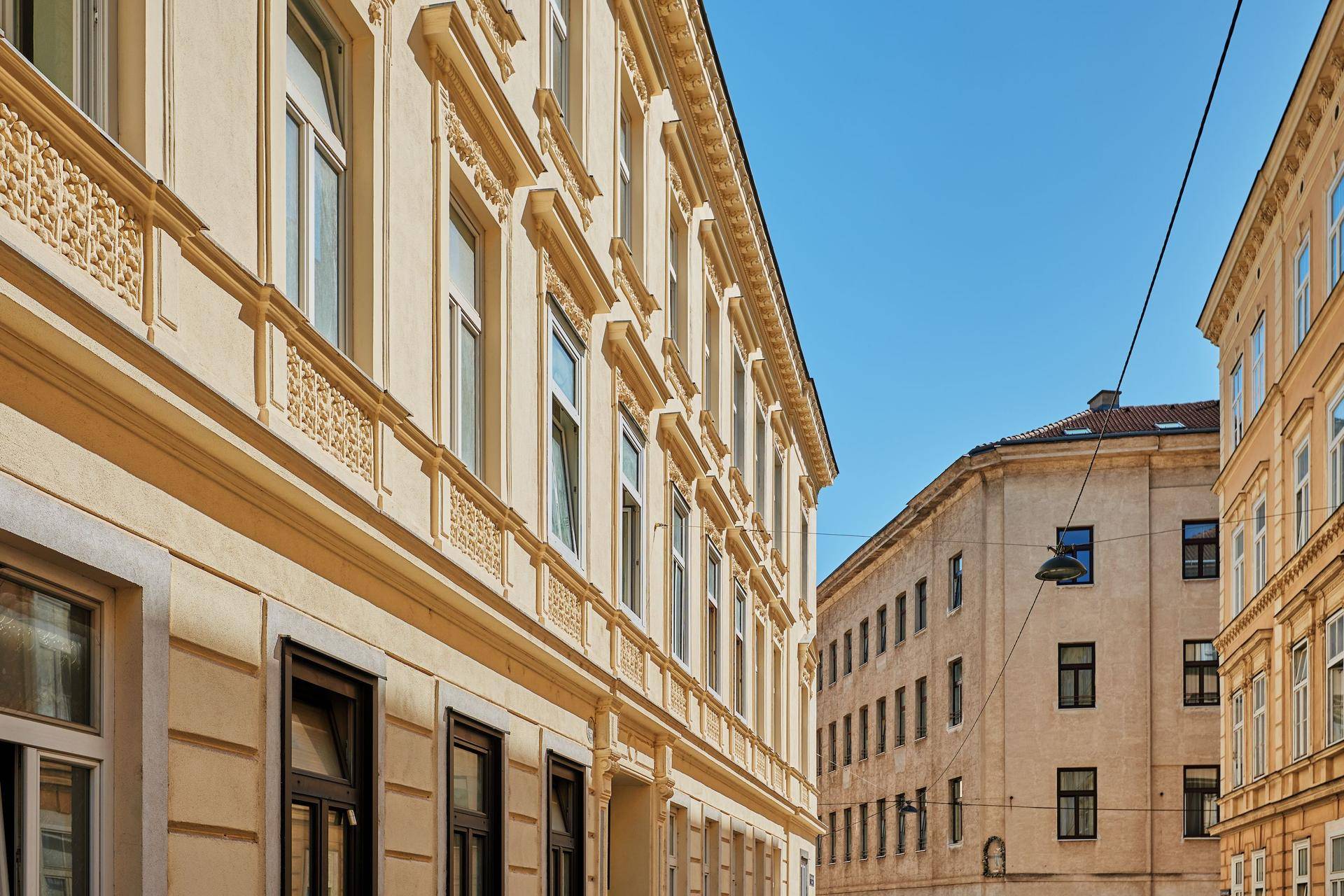 Seitenansicht der historischen Fassade mit Blick auf die Straße und angrenzende Gebäude unter blauem Himmel.