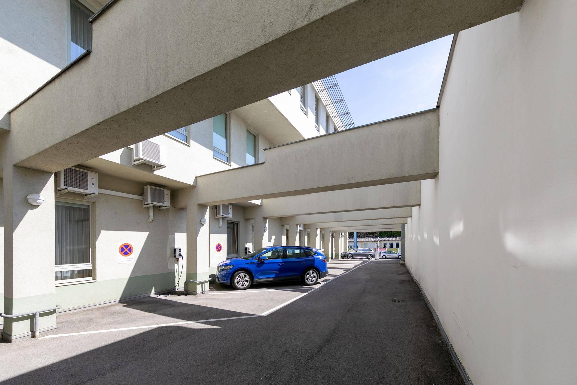 Überdachter Parkplatzbereich mit mehreren Stellplätzen und Ladesäulen für Elektrofahrzeuge.
