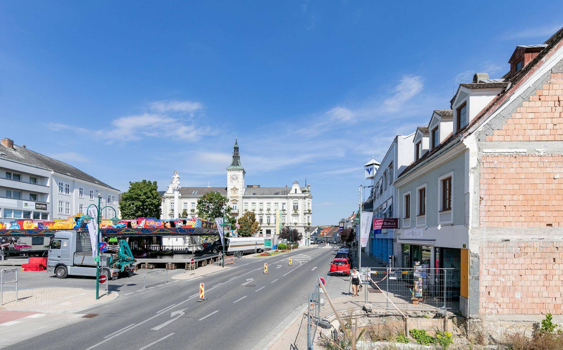 Weitläufige Straßenansicht einer Stadt mit historischen Gebäuden und einem belebten Platz.