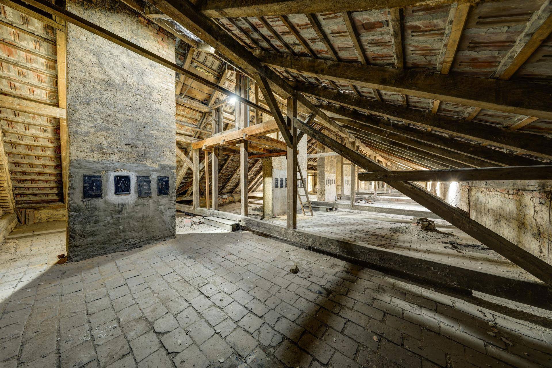 Geräumiger Dachboden mit freiliegenden Holzbalken, Ziegelboden und gemauertem Kamin.