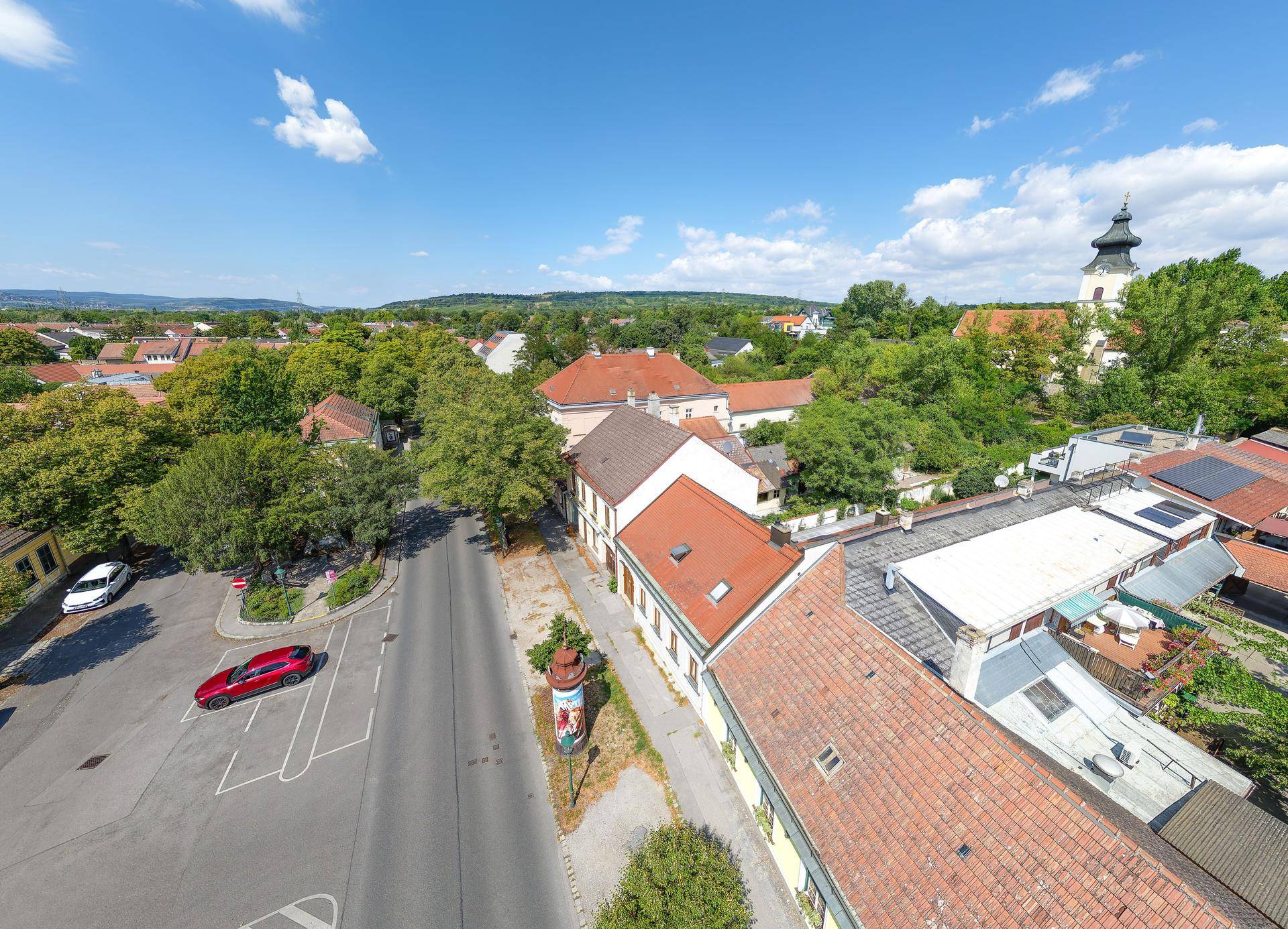 Panoramablick über die Wohngegend mit Straßen, Häusern und viel Grün unter blauem Himmel.