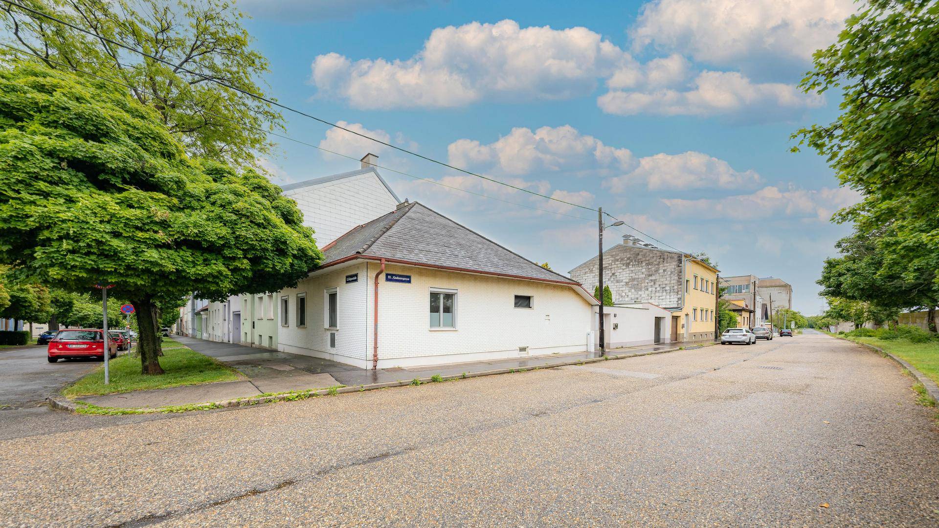 Ansicht des Wohnhauses von der Straße aus mit grüner Umgebung und Bäumen.