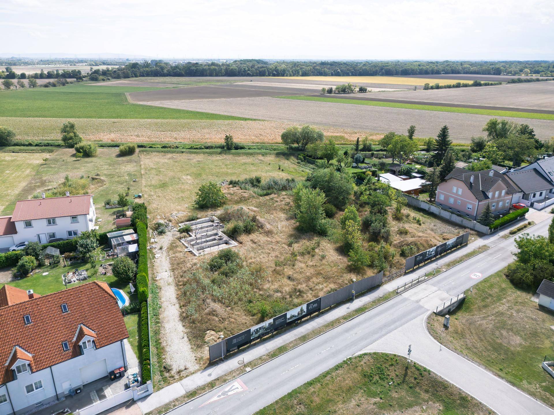Luftaufnahme eines unbebauten Grundstücks mit sichtbaren Fundamentresten, angrenzender Straße und ländlicher Umgebung.