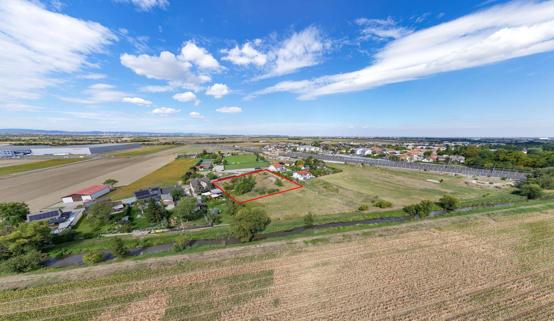 Weitläufige Luftaufnahme des Grundstücks mit Blick auf die umliegende Landschaft, eine Siedlung und weite Felder.
