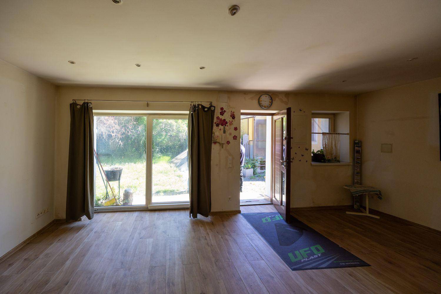 Geräumiges Wohnzimmer mit Laminatboden, großen Glastüren und direktem Zugang zum Garten.