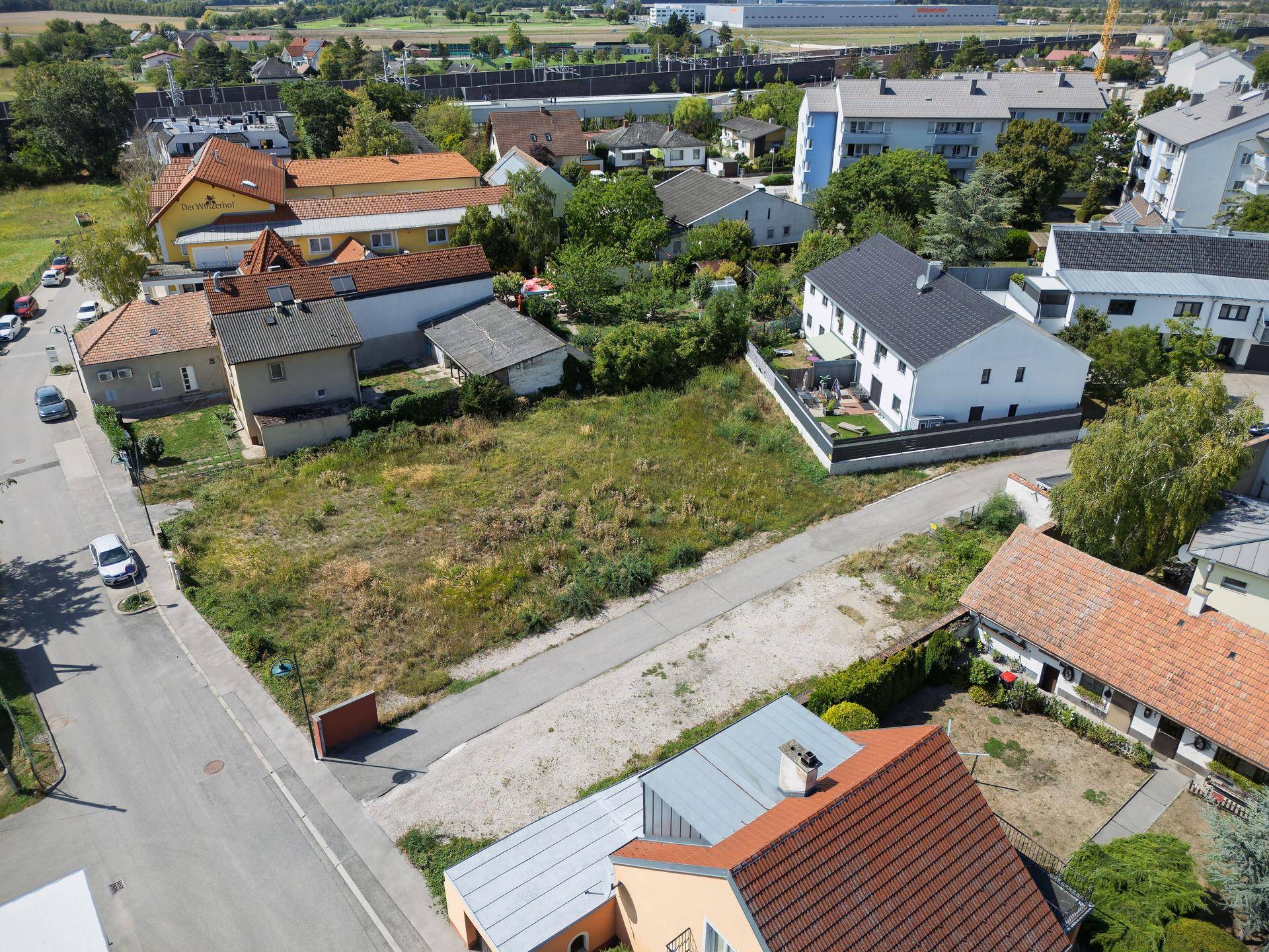 Weitläufige Luftaufnahme eines unbebauten Grundstücks in einer Wohnsiedlung mit Blick auf die Umgebung.