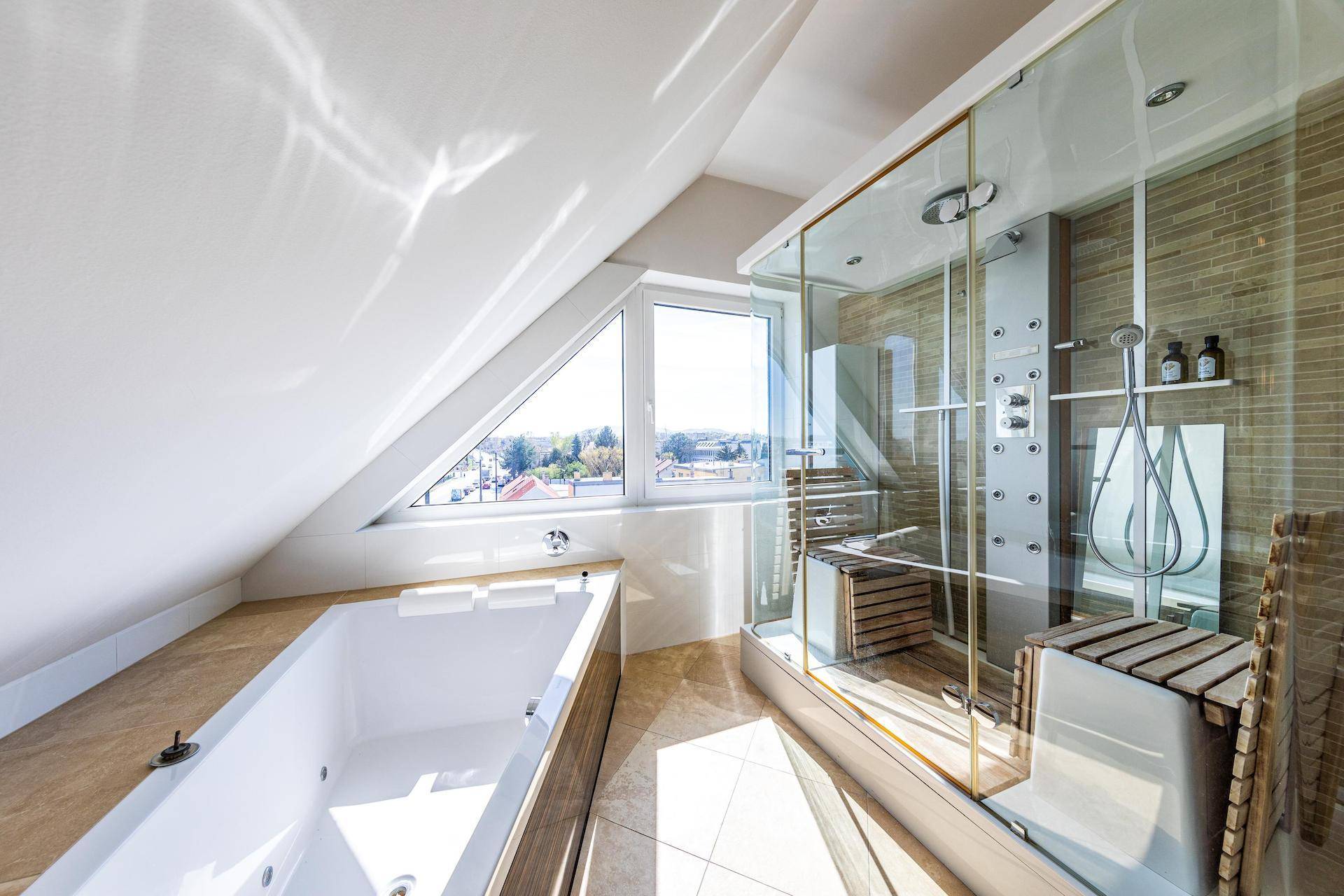 Modernes Badezimmer unter Dachschräge mit Badewanne, großer Duschkabine und Fenster mit Ausblick.