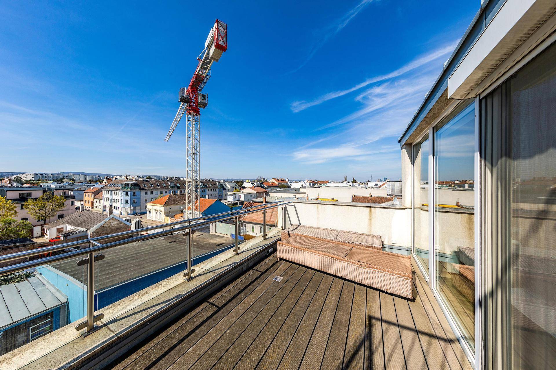 Große Dachterrasse mit Holzbelag, Sitzgelegenheiten und weitem Blick über die Stadt.